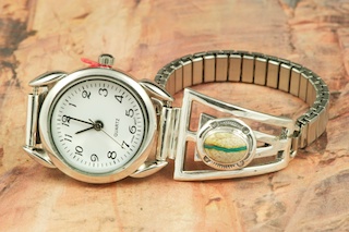 Genuine Boulder Turquoise set in Sterling Silver Watch Tips.  Ladies quartz watch with expandable watch band. The cabochons are Boulder Turquoise, you can see the veins of Turquoise running through the host rock. The Boulder Turquoise Mine is located in northeast Nevada. It was discovered in 1970 by a Shoshone sheep herder. Production is small due to the remote location and winter weather. Boulder Turquoise is valued for both it's beauty and rarity. Every stone is unique. Created by Navajo Artist Freddy Charley. Signed by the artist.